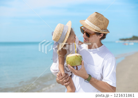 Father and daughter drink coconut water, walk and relax on beach during summer vacation. Happy family travel doing activities during holiday together. 121631861