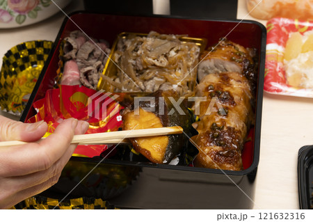 おせち料理を箸で重箱に詰める　 121632316