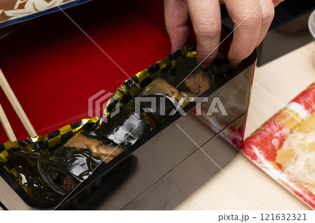 おせち料理を箸で重箱に詰める　 121632321