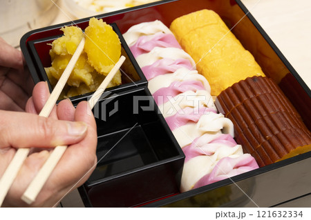 おせち料理を箸で重箱に詰める　 121632334