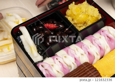 おせち料理を箸で重箱に詰める　 121632336