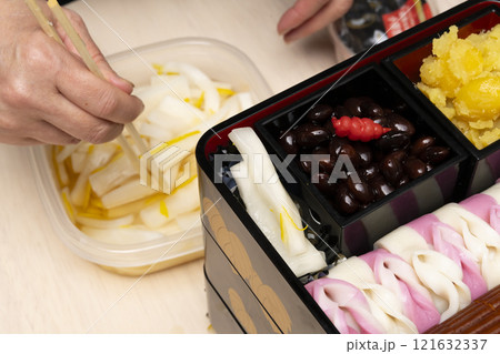 おせち料理を箸で重箱に詰める　 121632337