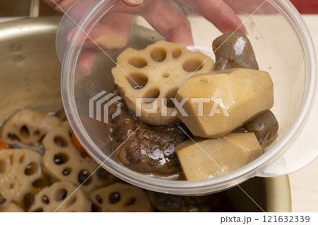 おせち料理を箸で重箱に詰める おせち料理を箸で重箱に詰める 121632339