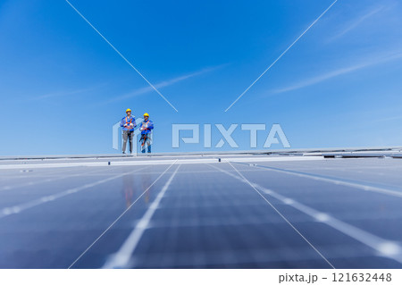 Technicians are installing and inspecting standards of solar panels on roof of an industrial factory. Electrical energy obtained from nature sunlight clean renewable energy. Technicians are installing and inspecting standards of solar panels on roof of an industrial factory. Electrical energy obtained from nature sunlight clean renewable energy. 121632448
