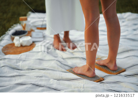 Relaxing wellness session on a picnic blanket in a serene outdoor setting Relaxing wellness session on a picnic blanket in a serene outdoor setting 121633517