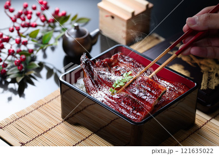 湯気立つうな重を箸で持ち上げたシズル感あふれる和食カット 121635022