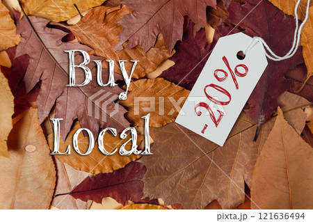 Tag with the word buy is hanging from a pile of leaves 121636494