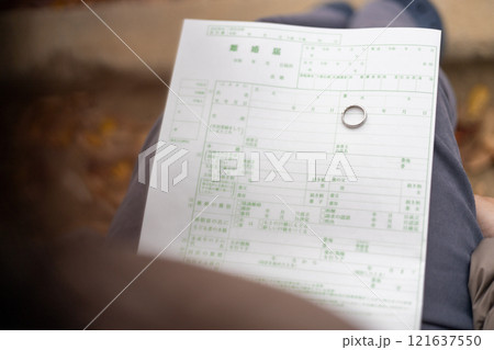 公園のベンチに座り込み、離婚届を眺める中高年女性 121637550