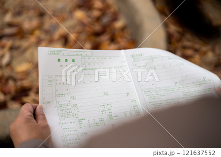 公園のベンチに座り込み、離婚届を眺める中高年女性 公園のベンチに座り込み、離婚届を眺める中高年女性 121637552