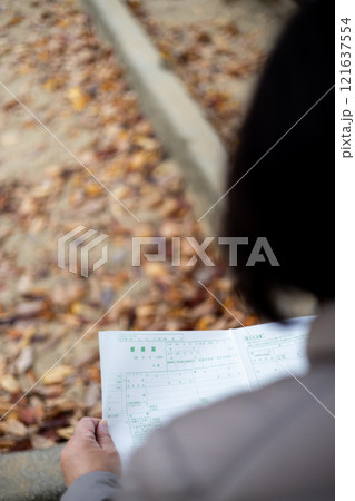 公園のベンチに座り込み、離婚届を眺める中高年女性 公園のベンチに座り込み、離婚届を眺める中高年女性 121637554