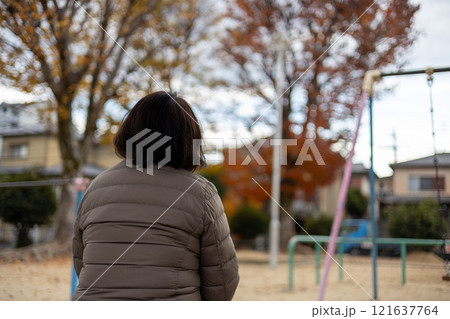 公園に座ってボーっとしている中高年女性の後ろ姿 121637764