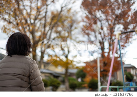 公園に座ってボーっとしている中高年女性の後ろ姿 121637766