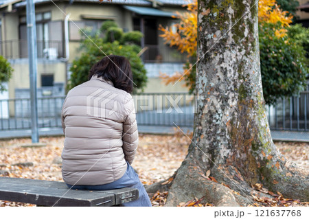 公園に座ってボーっとしている中高年女性の後ろ姿 公園に座ってボーっとしている中高年女性の後ろ姿 121637768