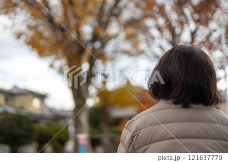 公園に座ってボーっとしている中高年女性の後ろ姿 121637770