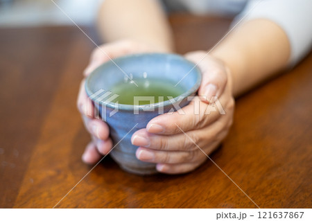 焼物の湯飲みを持ってお茶を飲もうとしている中高年女性の手元 焼物の湯飲みを持ってお茶を飲もうとしている中高年女性の手元 121637867