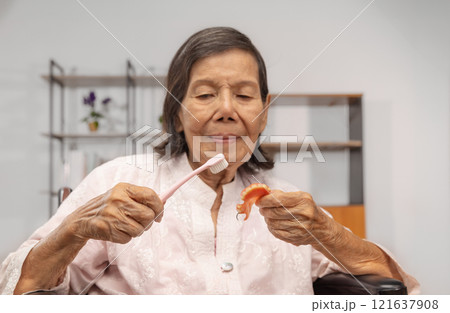 Elderly Woman Cleaning Dentures with a Toothbrush. Elderly Woman Cleaning Dentures with a Toothbrush. 121637908