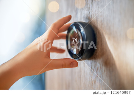 The hand reaching for the thermostat 121640997
