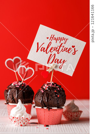 Cupcake love: Heart-themed treats on a vibrant red backdrop 121641166