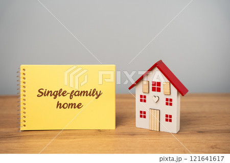 Single-family home concept. Standalone residential building designed to house one family or household. A notebook with an inscription near a miniature house. Real estate 121641617