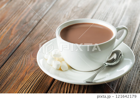 cocoa in white cup and marshmallows on saucer on table 121642179