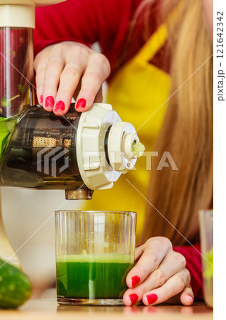Woman in kitchen making vegetable smoothie juice 121642342