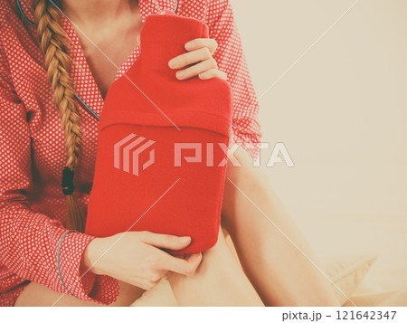 Woman holding warm red hot water bottle Woman holding warm red hot water bottle 121642347