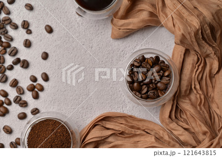 Top view fresh aromatic grain, ground and coffee drink in a small glasses, white background, brown cloth Top view fresh aromatic grain, ground and coffee drink in a small glasses, white background, brown cloth 121643815