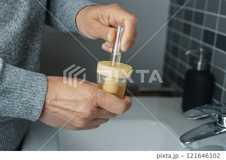 caucasian man fills a tube with a urine sample 121646102