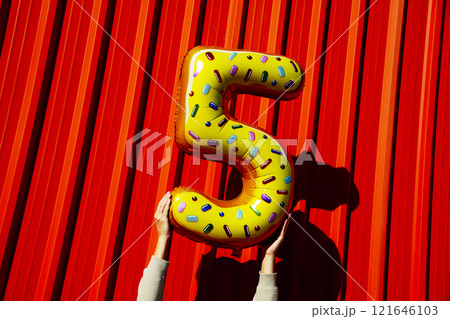 man holding a balloon in the shape of number 5 man holding a balloon in the shape of number 5 121646103