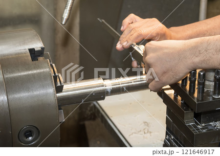 Close up scene the lath machine operator measuring dimension of turning parts by Vernier caliper. 121646917