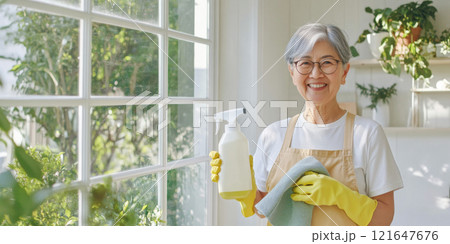 Elderly Asian woman holding cleaning supplies with cheerful expression, spring cleaning concept background Elderly Asian woman holding cleaning supplies with cheerful expression, spring cleaning concept background 121647676