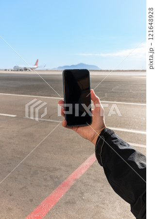 Girl holds a smartphone with a black screen close-up. Phone on the background of the airport with an airplane 121648928