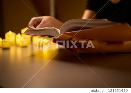 Indulging in Cozy Reading Under Candlelight for a Relaxing and Peaceful Evening Escape 121651459