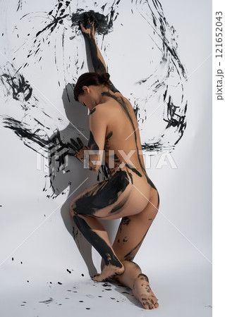 A woman expresses despair through painting a picture on the wall 121652043