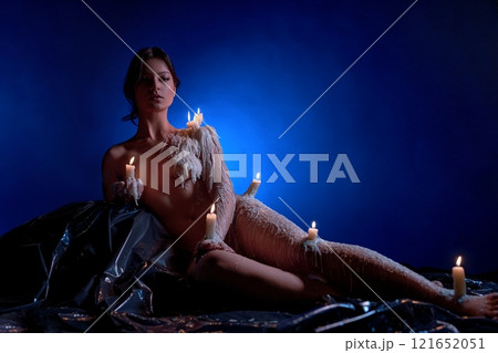 Strong confident woman with burning candles in her hands looking into camera Strong confident woman with burning candles in her hands looking into camera 121652051