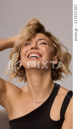 Confident Woman with Short Wavy Hair Wearing a Stylish Black Outfit in a Studio Setting Confident Woman with Short Wavy Hair Wearing a Stylish Black Outfit in a Studio Setting 121652367