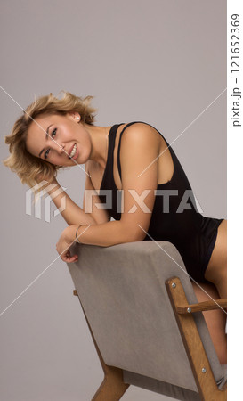 Confident Woman with Short Wavy Hair Wearing a Stylish Black Outfit in a Studio Setting 121652369