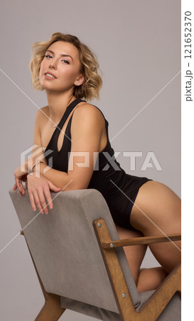 Confident Woman with Short Wavy Hair Wearing a Stylish Black Outfit in a Studio Setting Confident Woman with Short Wavy Hair Wearing a Stylish Black Outfit in a Studio Setting 121652370