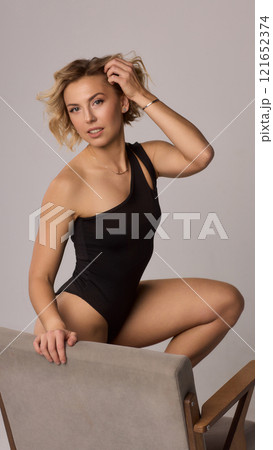 Confident Woman with Short Wavy Hair Wearing a Stylish Black Outfit in a Studio Setting 121652374
