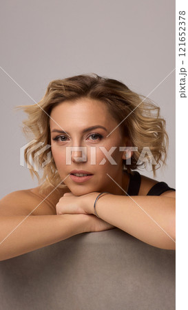 Confident Woman with Short Wavy Hair Wearing a Stylish Black Outfit in a Studio Setting 121652378