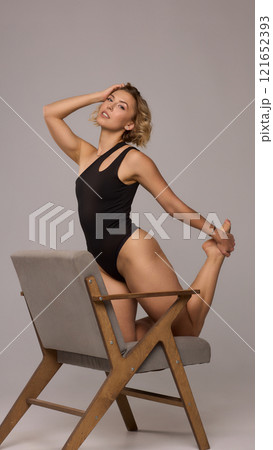 Confident Woman with Short Wavy Hair Wearing a Stylish Black Outfit in a Studio Setting 121652393
