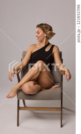 Confident Woman with Short Wavy Hair Wearing a Stylish Black Outfit in a Studio Setting 121652398