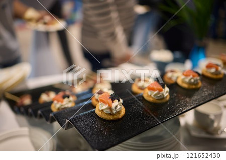 Assorted pastries such as jam tarts and layered desserts beautifully presented on slate trays 121652430