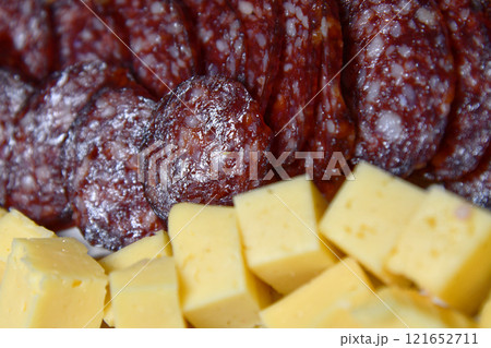 Sausage slices on wooden board with different snacks. Sausage slices on wooden board with different snacks. 121652711