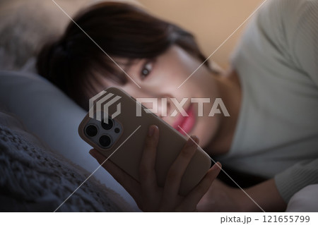 夜中にスマホを見て睡眠が足りず寝不足になってしまう女性のクローズアップ 夜中にスマホを見て睡眠が足りず寝不足になってしまう女性のクローズアップ 121655799