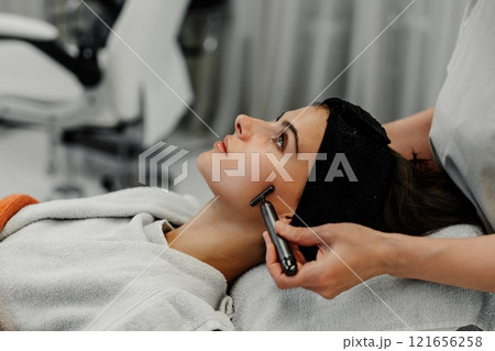 Woman receiving facial massage in beauty salon. 121656258