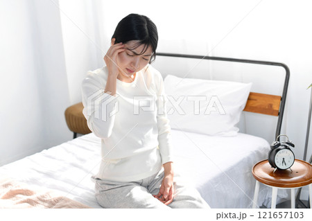 ベッドで頭痛に悩む若いアジア人女性 ベッドで頭痛に悩む若いアジア人女性 121657103