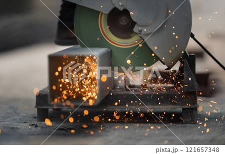 Worker cutting steel rectangular pipe in construction site. 121657348