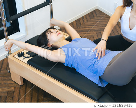 マシンピラティスのレッスンを受ける女性 マシンピラティスのレッスンを受ける女性 121659419