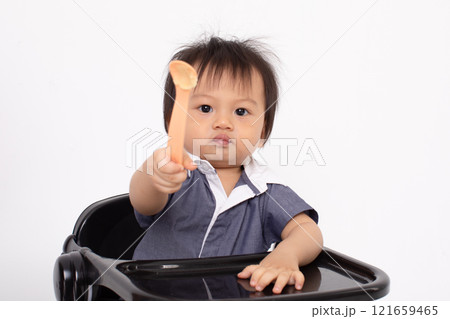 Cute Asian Baby Holding Spoon While Sitting in High Chair 121659465
